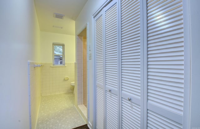 hall featuring tile patterned floors and tile walls