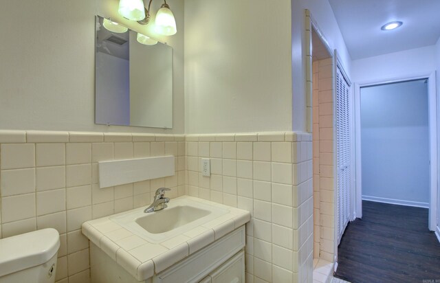 bathroom with vanity, toilet, tile walls, and hardwood / wood-style floors