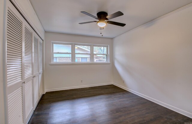 unfurnished bedroom featuring a closet, ornamental molding, dark wood-type flooring, and ceiling fan