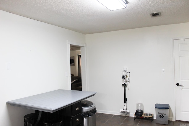 interior space with a textured ceiling and dark tile patterned flooring