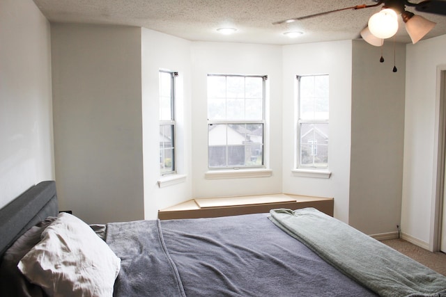 bedroom with ceiling fan, carpet flooring, and a textured ceiling