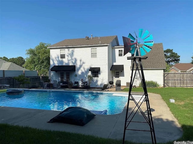 back of property with a patio, a fenced in pool, and a yard