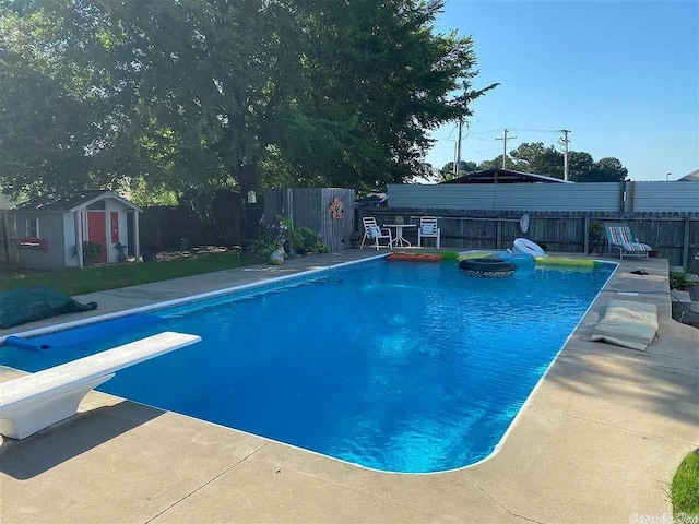 view of swimming pool with a shed, a patio, and a diving board