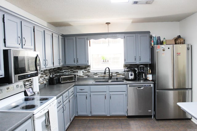 kitchen with decorative backsplash, appliances with stainless steel finishes, a textured ceiling, dark tile patterned flooring, and sink