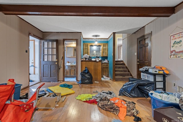 interior space featuring beam ceiling, hardwood / wood-style floors, a textured ceiling, and wood walls