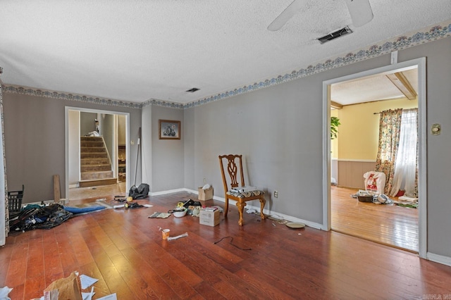 living area with a textured ceiling, hardwood / wood-style flooring, and ceiling fan