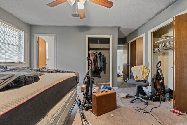 bedroom with a textured ceiling, light colored carpet, and ceiling fan