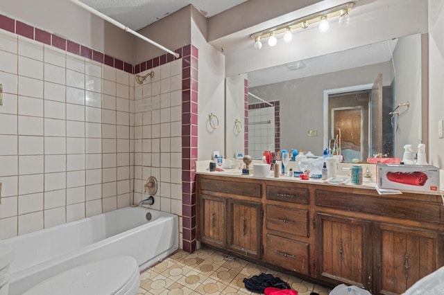 full bathroom featuring a textured ceiling, toilet, vanity, tiled shower / bath combo, and tile patterned floors