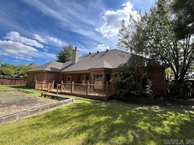 back of property featuring a deck and a lawn