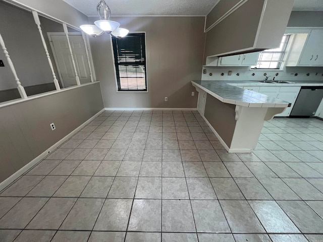 kitchen with tile countertops, hanging light fixtures, kitchen peninsula, a breakfast bar, and white cabinets