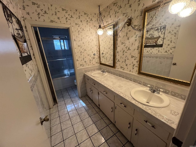 full bathroom featuring tile patterned floors, toilet, vanity, enclosed tub / shower combo, and a textured ceiling