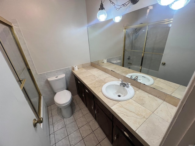 full bathroom featuring shower / bath combination with glass door, tile walls, toilet, vanity, and tile patterned flooring