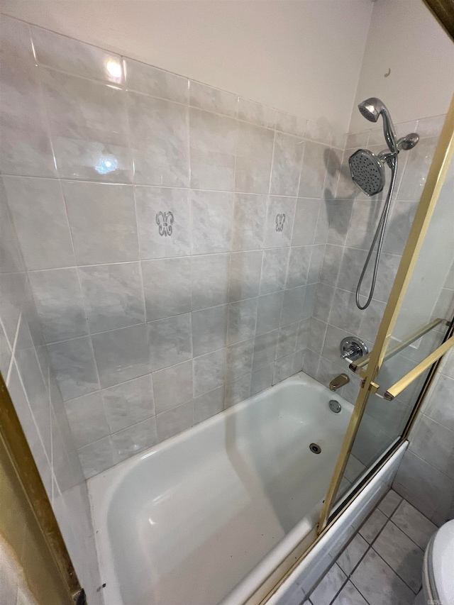 bathroom featuring toilet, tiled shower / bath combo, and tile patterned flooring