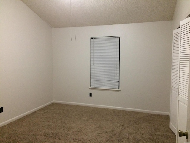 interior space with lofted ceiling, a textured ceiling, and dark carpet