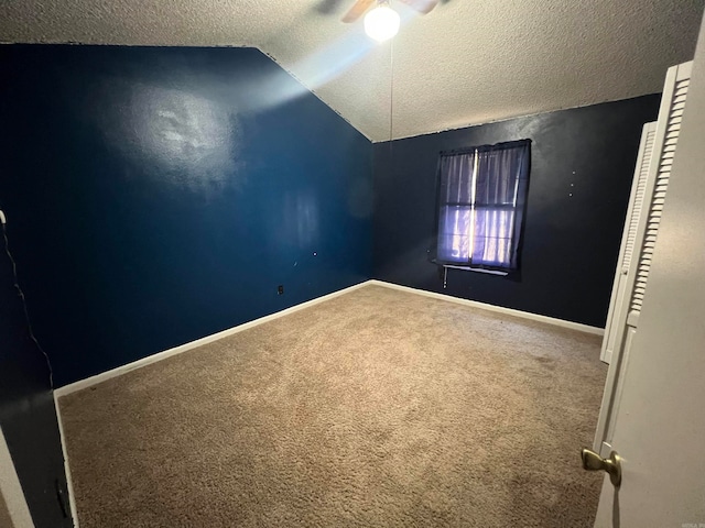 carpeted spare room with lofted ceiling, a textured ceiling, and ceiling fan