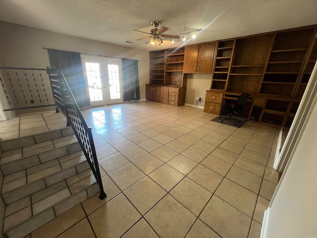 unfurnished living room featuring light tile patterned flooring, french doors, built in desk, a textured ceiling, and ceiling fan