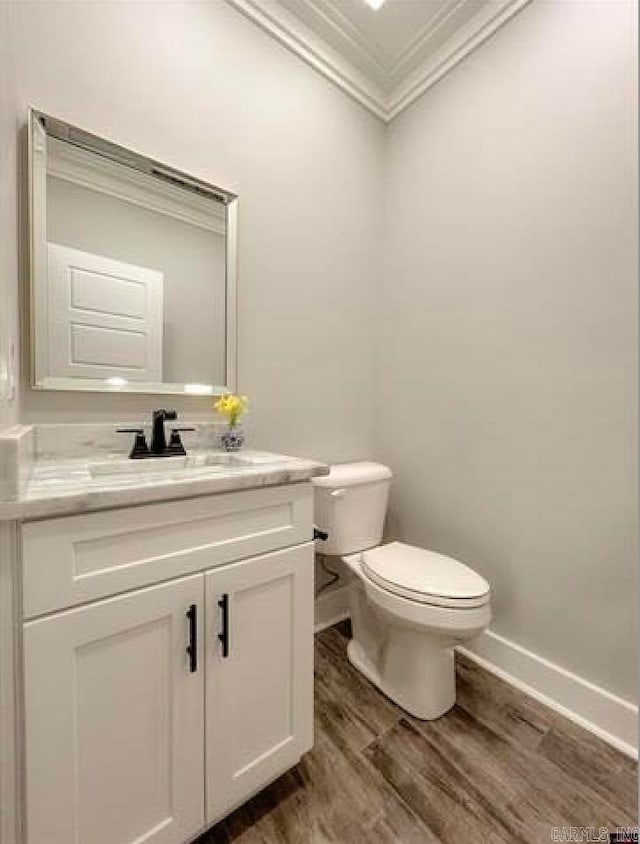 bathroom featuring vanity, hardwood / wood-style floors, crown molding, and toilet