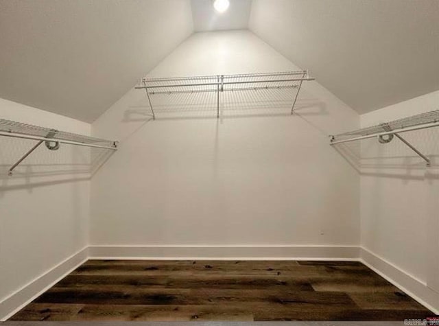 walk in closet with dark hardwood / wood-style floors and vaulted ceiling