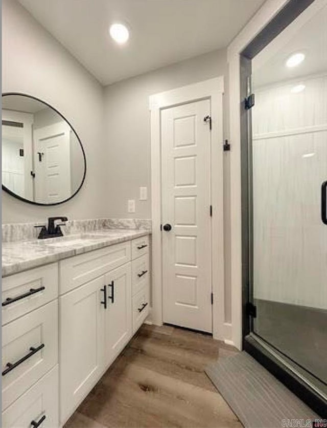 bathroom with vanity, a shower with shower door, and wood-type flooring