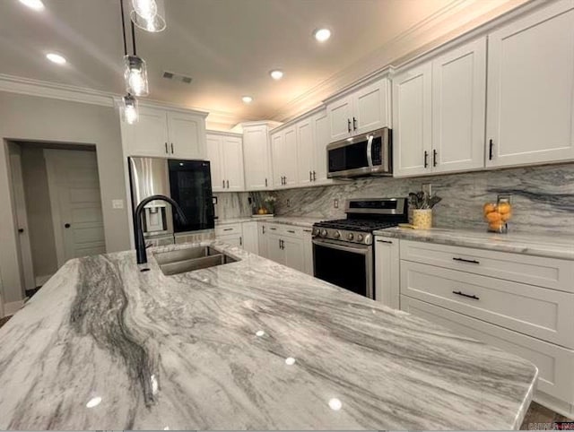 kitchen with appliances with stainless steel finishes, sink, decorative light fixtures, white cabinets, and light stone counters