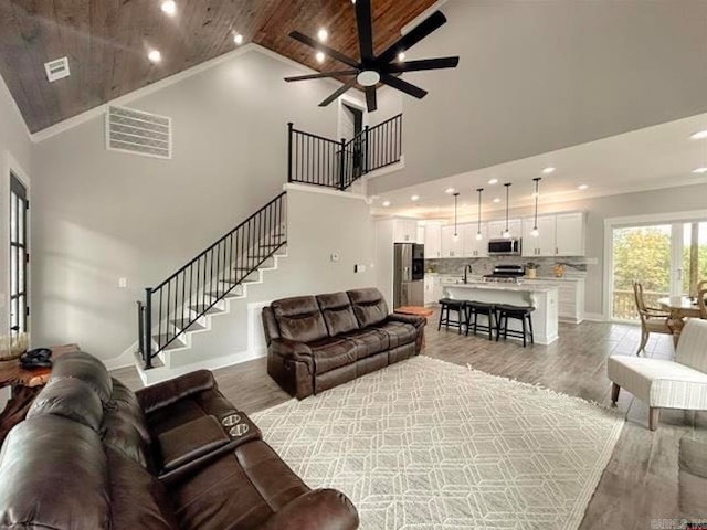 living room featuring wood-type flooring, wooden ceiling, sink, high vaulted ceiling, and ceiling fan