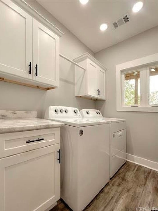 washroom with washing machine and dryer, cabinets, and dark hardwood / wood-style flooring