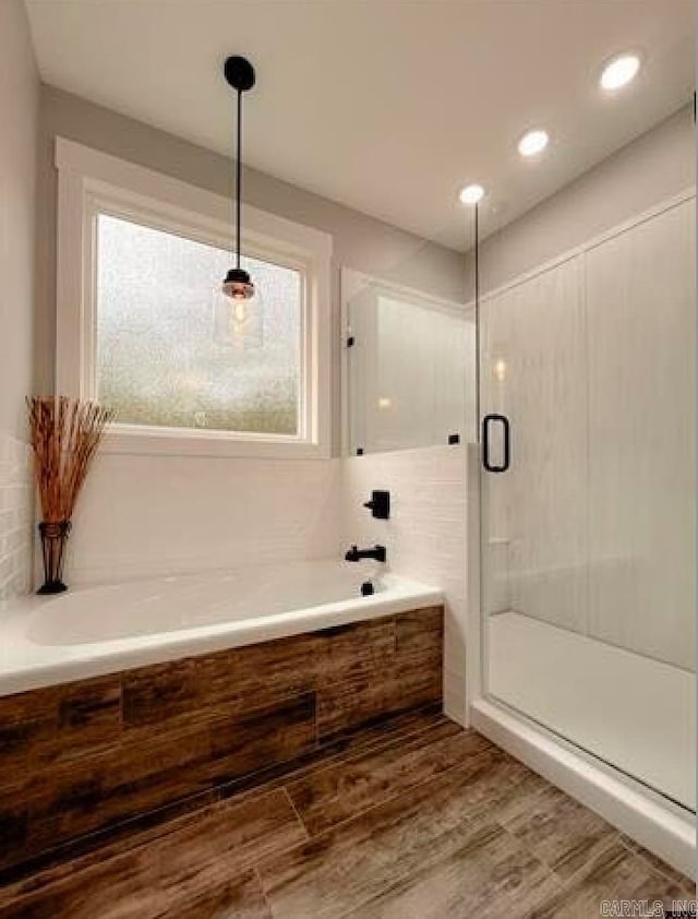 bathroom featuring wood-type flooring, plenty of natural light, and separate shower and tub