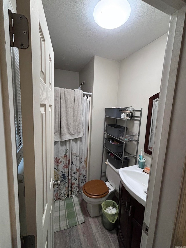 bathroom with toilet, hardwood / wood-style floors, vanity, a textured ceiling, and walk in shower