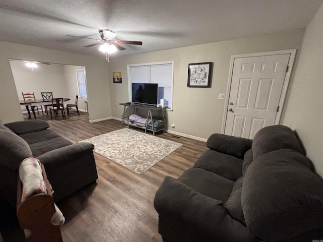 living room with dark hardwood / wood-style floors, a textured ceiling, and ceiling fan