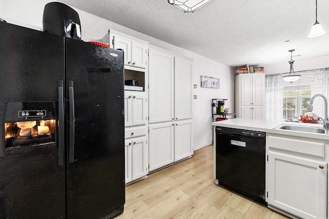 kitchen with black appliances, white cabinets, decorative light fixtures, and light wood-type flooring