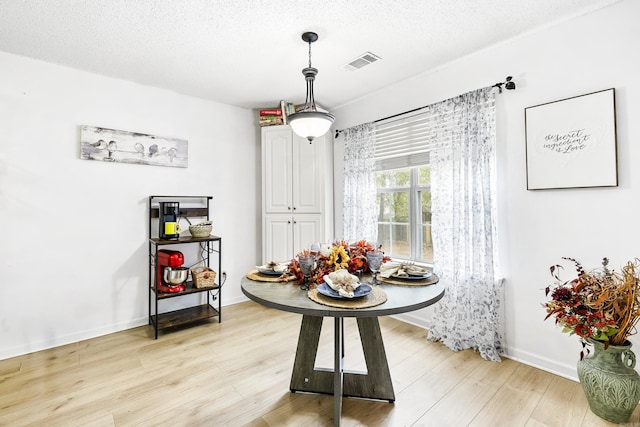 dining room with light hardwood / wood-style flooring and a textured ceiling