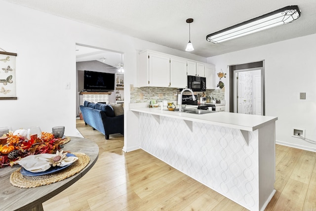 kitchen with light wood-type flooring, kitchen peninsula, white cabinetry, pendant lighting, and a breakfast bar area