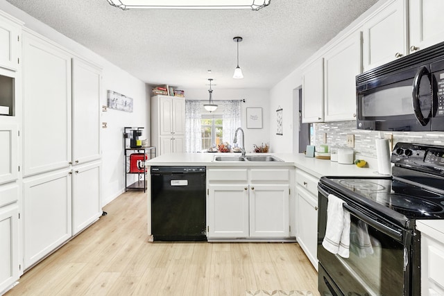 kitchen with black appliances, sink, light wood-type flooring, pendant lighting, and white cabinets