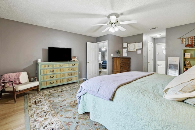 bedroom featuring a textured ceiling, hardwood / wood-style flooring, connected bathroom, and ceiling fan