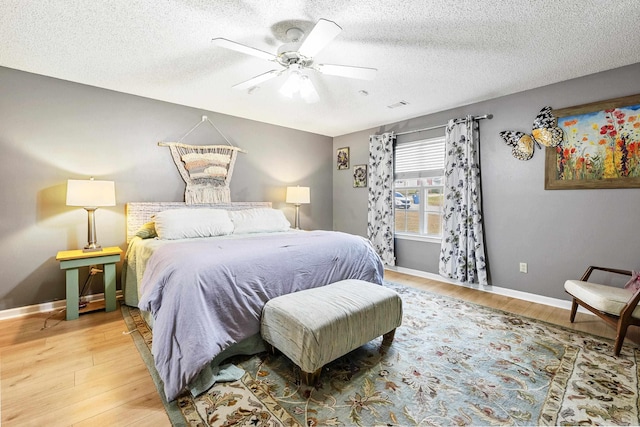 bedroom with ceiling fan, a textured ceiling, and hardwood / wood-style floors