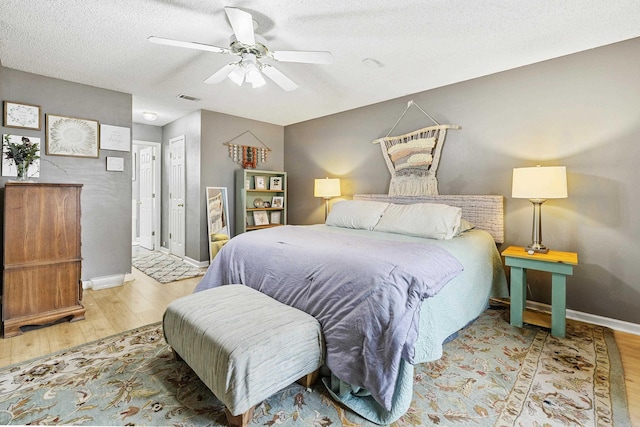 bedroom with a textured ceiling, light wood-type flooring, and ceiling fan