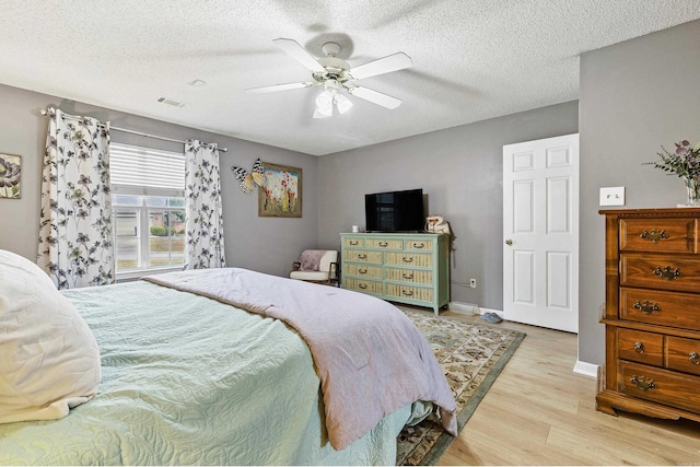 bedroom featuring light hardwood / wood-style flooring, a textured ceiling, and ceiling fan