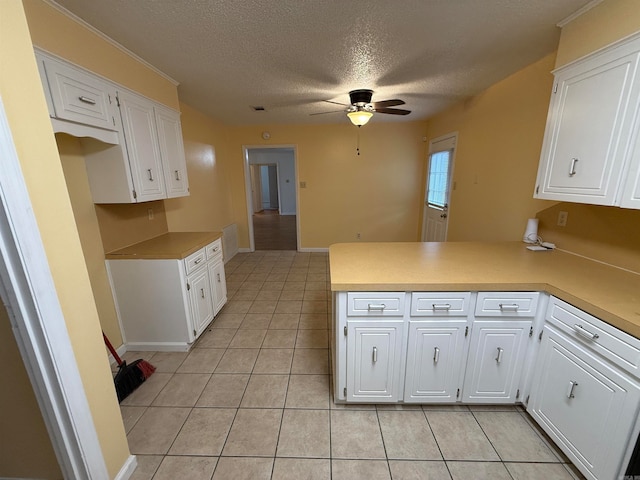 kitchen featuring a textured ceiling, light tile patterned floors, kitchen peninsula, and white cabinets