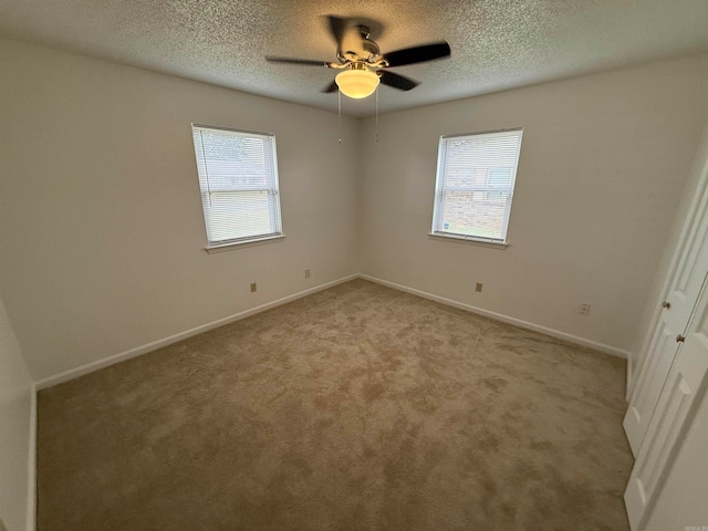 carpeted empty room with ceiling fan, a textured ceiling, and a wealth of natural light