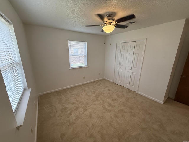 unfurnished bedroom featuring a closet, ceiling fan, light carpet, and multiple windows