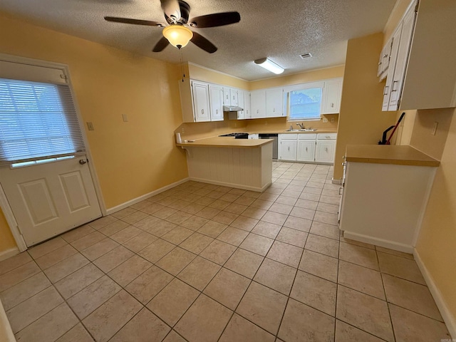 kitchen with stainless steel dishwasher, white cabinets, a textured ceiling, and light tile patterned floors