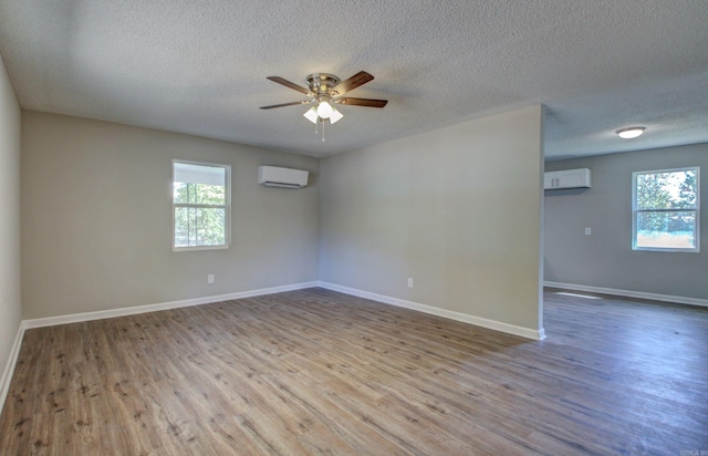 spare room featuring a wall mounted air conditioner, a textured ceiling, and light hardwood / wood-style floors