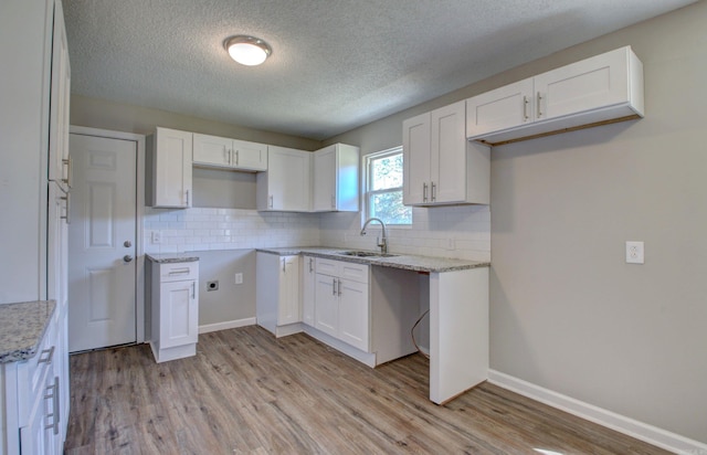 kitchen featuring sink, tasteful backsplash, light hardwood / wood-style flooring, and white cabinets