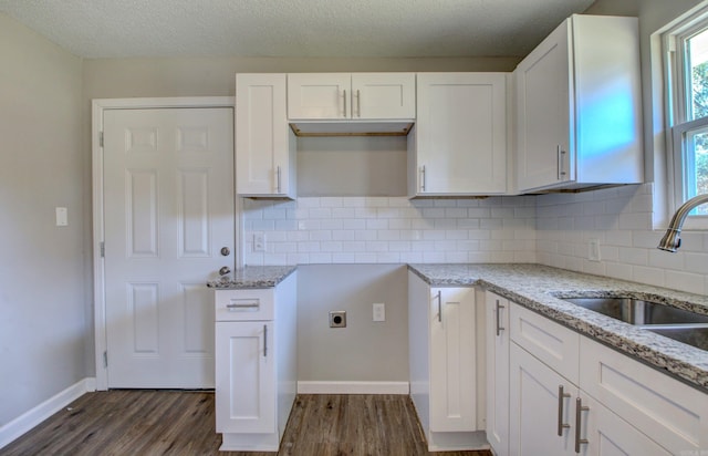 kitchen featuring sink, light stone countertops, white cabinetry, a textured ceiling, and dark hardwood / wood-style flooring