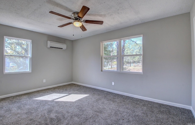 carpeted spare room featuring a wall unit AC, a textured ceiling, a healthy amount of sunlight, and ceiling fan