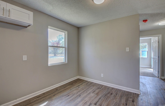 empty room with light hardwood / wood-style flooring and a textured ceiling