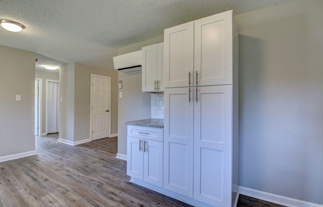 kitchen with decorative backsplash, hardwood / wood-style floors, white cabinetry, and light stone counters