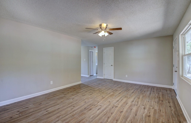 unfurnished room with a textured ceiling, light wood-type flooring, and ceiling fan