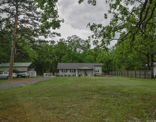 view of yard with an outdoor structure, fence, and driveway