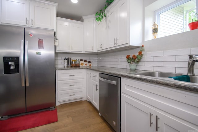 kitchen featuring white cabinets, stainless steel appliances, decorative backsplash, and light wood-style flooring